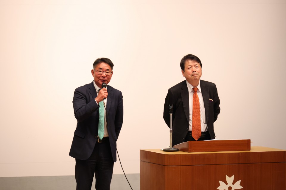 あいさつする玉井のぶまさ氏(左) 平岡秀夫