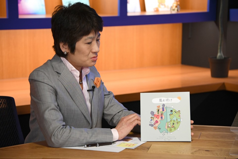 大林さんが紹介してくれた、絵本『風よ吹け」を手に取る西村幹事長 20220318_114554-.jpg